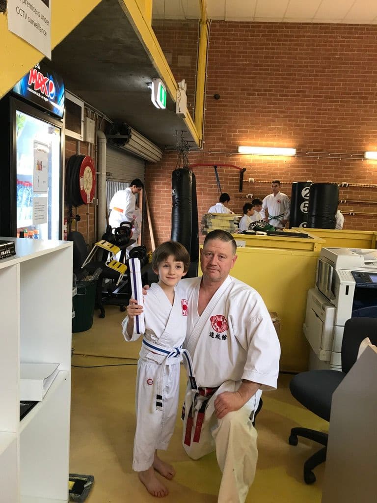 child earning karate belt with instructor showing confidence and progress