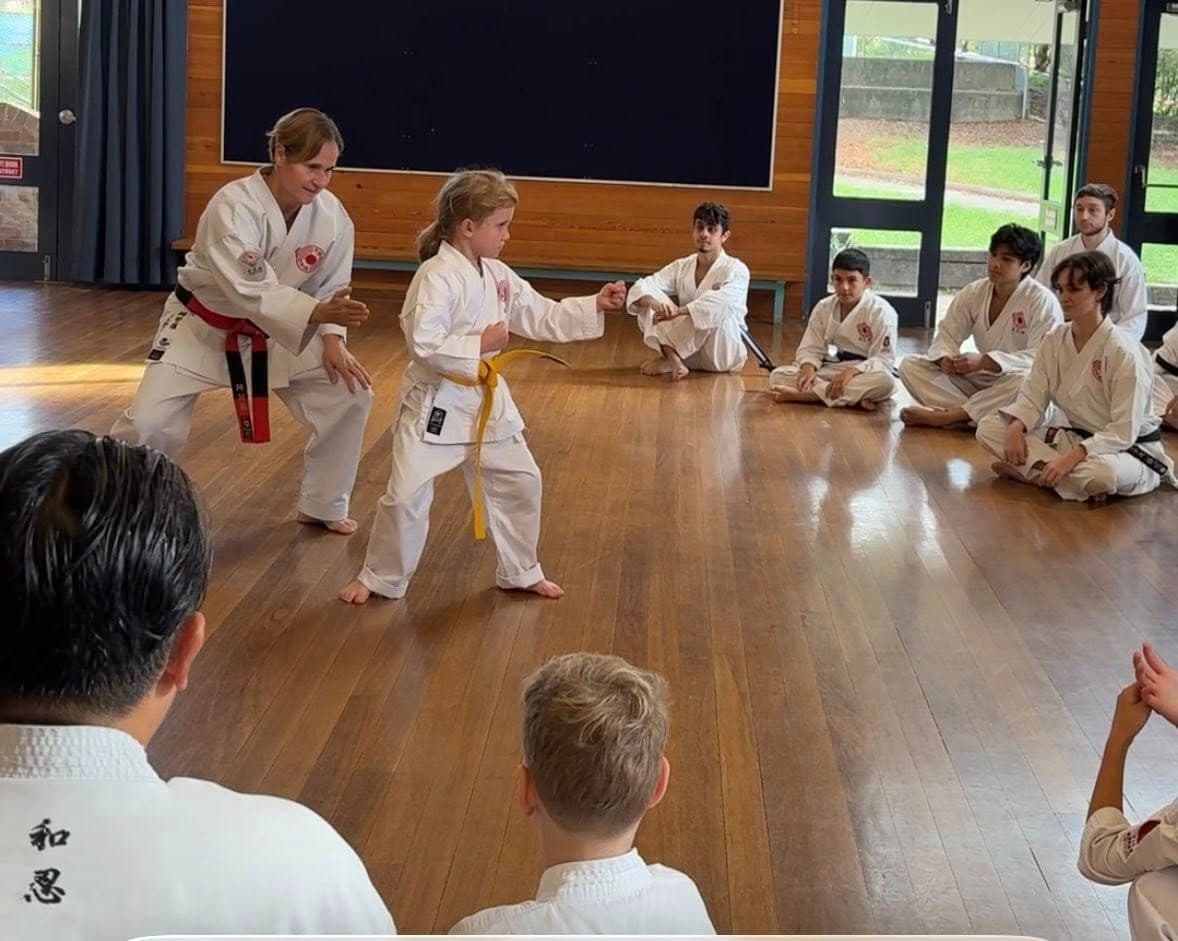 child practicing karate with instructor showing confidence development in dojo class